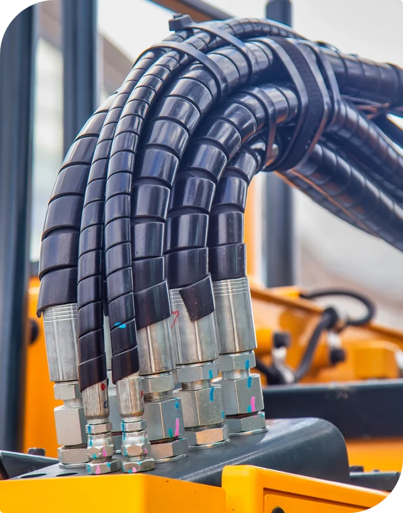 Blå spirallindade hydraulslangar på en gul maskin